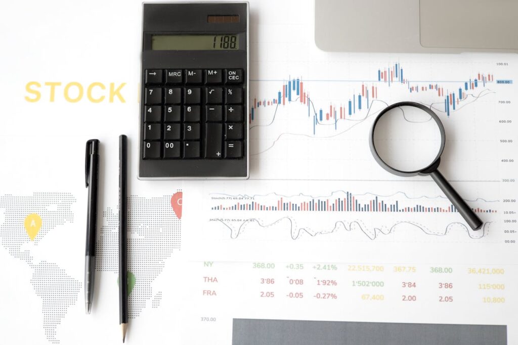 pexels-photo-6801636 Flat lay of stock market analysis tools including calculator, graphs, and magnifying glass.